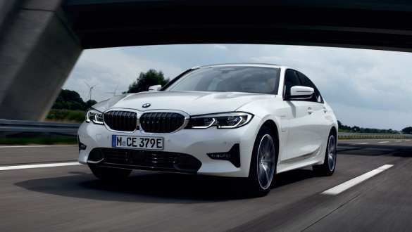 Plug-in hybrid BMW 3 Series Sedan 2021 G20 three-quarter front view driving Plug-in hybrid BMW 3 Series Sedan 2021 G20 three-quarter front view driving on the street