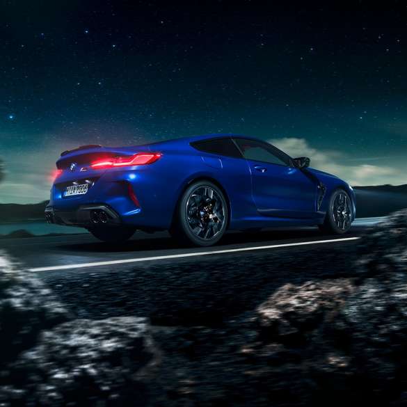 BMW M8 Coupé, three-quarter side view. BMW M8 Coupé in Marina Bay Blue metallic, driving three-quarter side view in front of starry sky.