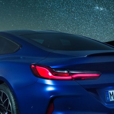 M rear spoiler BMW M8 Coupé in Marina Bay Blue metallic, nightly close-up of shoulder section with M rear spoiler in Carbon.