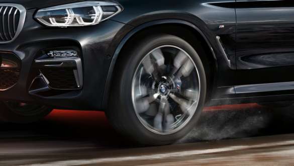 BMW X3 M40i side view. BMW X3 M40i in Black Sapphire metallic, driving, exterior, side view with rotating light alloy wheel.