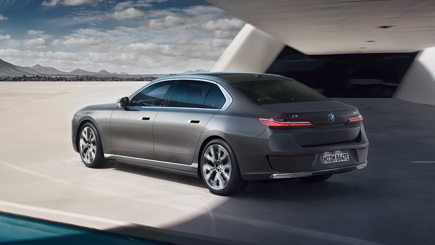 BMW i7 Sedan G70 BMW Individual Oxid grey metallic 3/4 rear view standing in front of building BMW i7 Sedan package 3/4 rear view