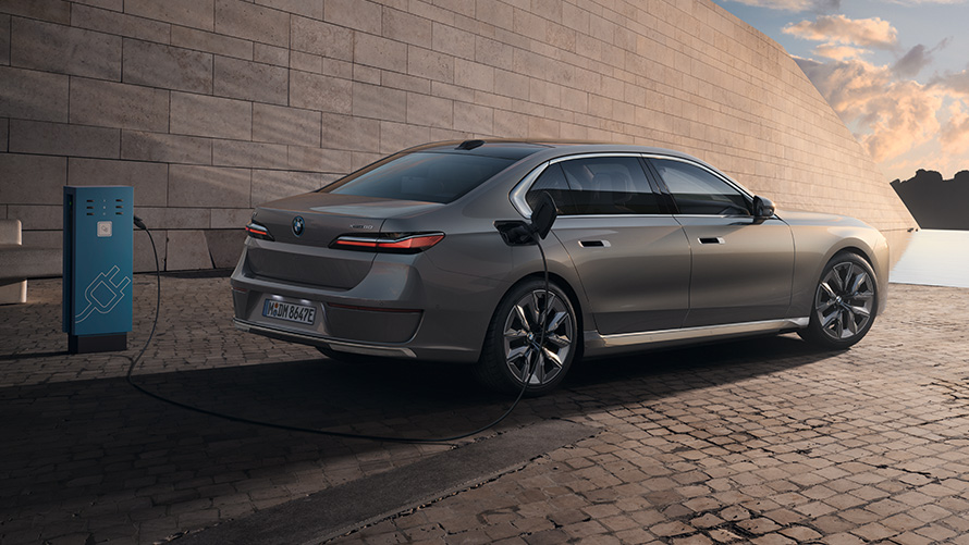 BMW i7 Sedan G70 3/4 side view from rear BMW i7 Sedan G70 BMW Individual Oxid grey metallic 3/4 side view from rear at charging station