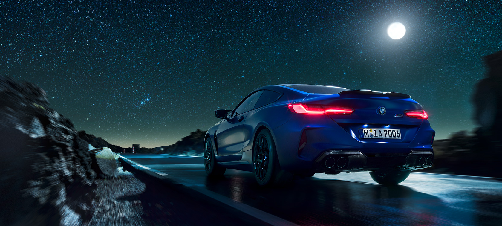 BMW M8 Coupé, rear view. BMW M8 Coupé, rear view, driving at night with full moon.