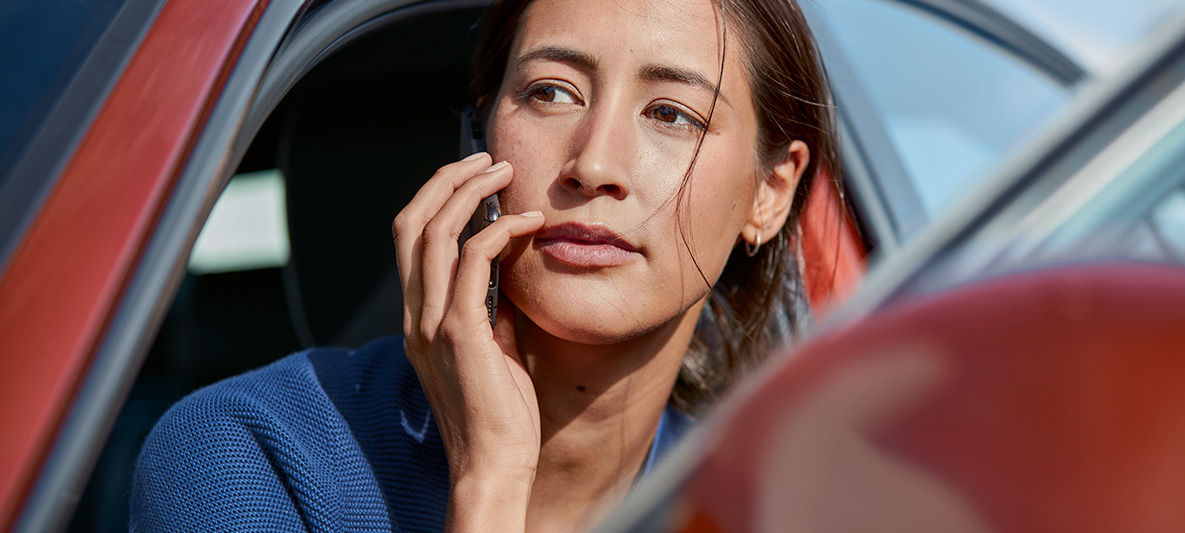 BMW Accident Assistance. A woman getting out of her BMW whilst on the phone.