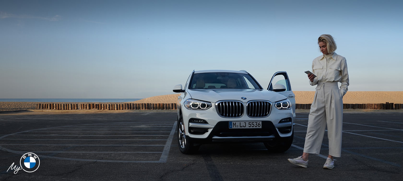 Woman using My BMW app in front of BMW.